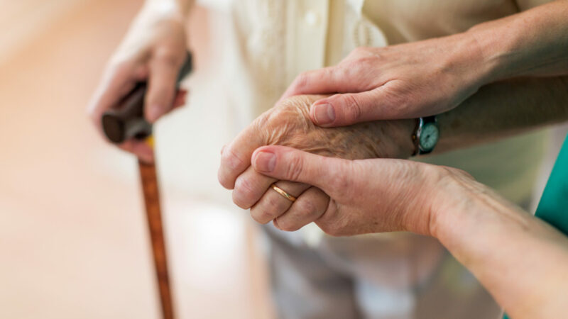 Nurse consoling her elderly patient by holding her hands